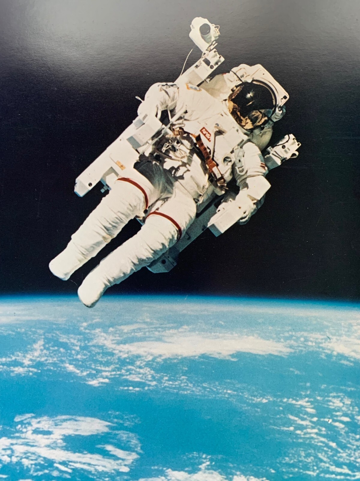 Three 8″x10″ photographs of the Manned Maneuvering Unit (MMU) in flight